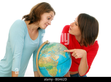 zwei Freundinnen mit Globus, auf der Suche nach einem Urlaubsziel. Eine Frau zeigt auf einen Platz auf der ganzen Welt während der andere Ske sieht Stockfoto