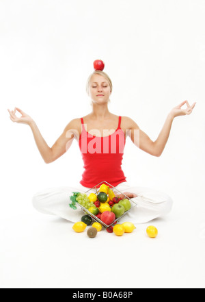 gesunden Lebensstil mit Früchten und Yoga. Junge, blonde Frau mit Früchten und ein roter Apfel auf dem Kopf Stockfoto