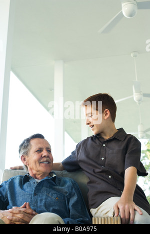 Großvater und Enkel sitzen zusammen auf der Veranda, beide Lächeln Stockfoto