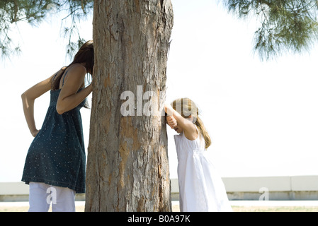 Zwei Schwestern Versteckspiel, spähen einer um Baum wie die anderen Grafen Stockfoto