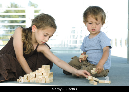 Bruder und Schwester sitzen auf dem Boden, zusammen mit Bausteinen zu spielen Stockfoto