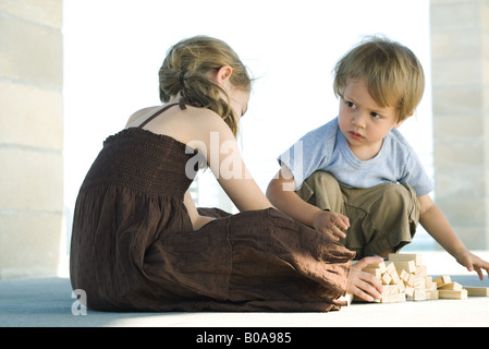 Jungen und Mädchen sitzen auf Boden, spielen mit Bausteinen Stockfoto