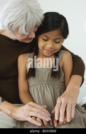 Großmutter umarmen Enkelin, Hand in Hand, beide auf der Suche nach unten Stockfoto