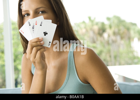 Teenager-Mädchen mit Karten vor Gesicht, alle Asse, Blick in die Kamera Stockfoto