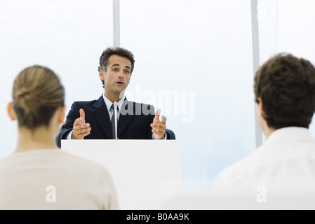 Mann spricht am Rednerpult, Publikum sitzt im Vordergrund Stockfoto