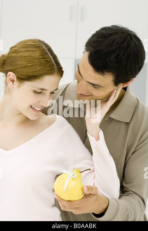 Junges Paar in der Küche, Mann reichte Frau eine Birne mit einem Bogen auf Sie Stockfoto