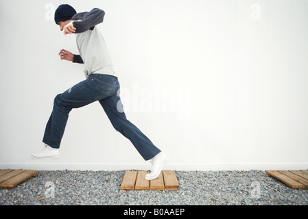Junger Mann läuft auf Fußweg in Kies, Seitenansicht Stockfoto