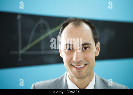 Mann lächelnd in die Kamera, Diagramm gezeichnet auf Tafel im Hintergrund Stockfoto