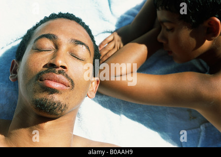 Vater und Sohn auf dem Boden liegend, Augen geschlossen, Nahaufnahme Stockfoto
