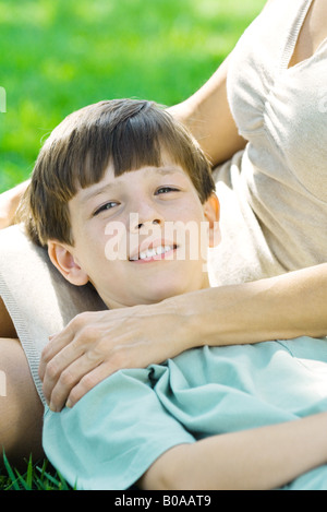 Junge auf Mutters Schoß, Kopf ruht lächelnd in die Kamera, Nahaufnahme Stockfoto
