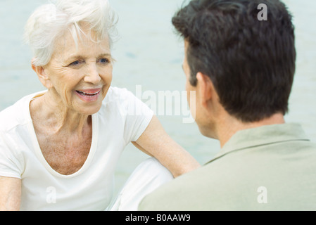 Ältere Frau sitzt gegenüber Mensch, Lächeln Stockfoto