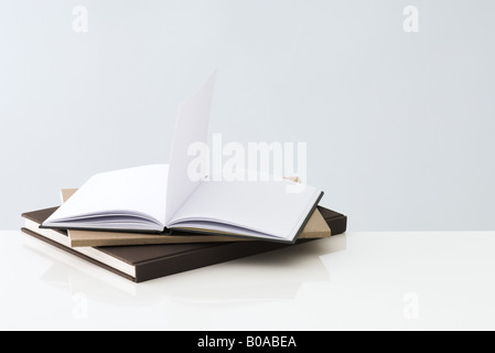 Stapel von Büchern, ein offenes Buch mit leeren Seiten innerhalb Stockfoto