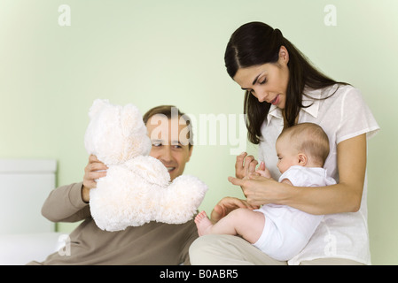 Mutter Vater hält Teddybär, lächelnd Säugling auf Schoß, halten Stockfoto