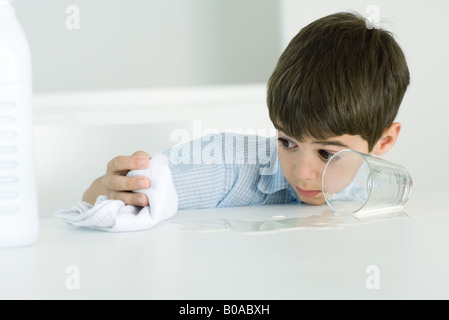 Kleinen Jungen wischen Sie verschüttete Milch mit Handtuch Stockfoto