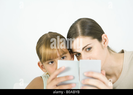 Frau und Mädchen Wange an Wange in die Hand Spiegel suchen Stockfoto