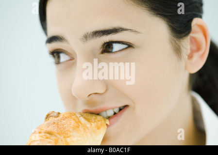 Junge Frau Essen Croissant, close-up Stockfoto