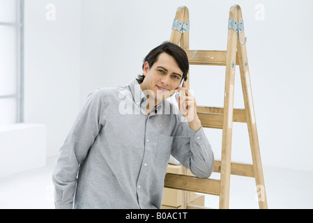 Mann gelehnt Leiter, mit Handy, lächelt in die Kamera Stockfoto