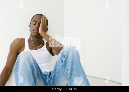 Teenboy hören, Kopfhörer, Augen geschlossen, Hand auf Gesicht Stockfoto