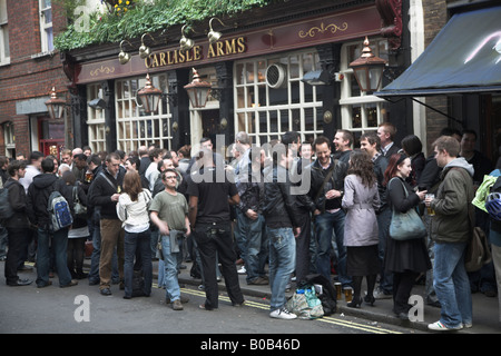 Trinker spill heraus auf der Straße vor Carlisle Arms Pub in Bateman Street, Soho, London Stockfoto