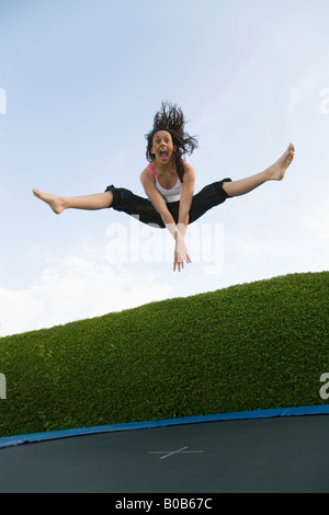 Junge Frau Trampolin; ein junges Mädchen im Alter von 16 Jahren Dumping auf einem Trampolin, Großbritannien Stockfoto