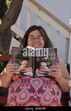 Schwangere Frau liest "Your Amazing Neugeborenen" Buch Stockfoto