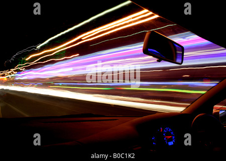 Straßenbeleuchtung, Verkehrs- und Ladenfronten produzieren atemberaubende Lichtspuren als die Kamera Streifen durch in einem schnell fahrenden Auto Stockfoto