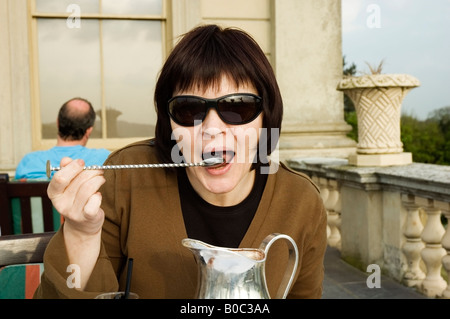 Close-up Portrait von Frauen Essen Kirschrot aus einem viktorianischen, langen, silbernen Löffel, England, Großbritannien, UK Stockfoto