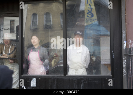 Mitarbeiter eines chinesischen Restaurants in Bushwick, Brooklyn schauen aus dem Fenster auf eine Osterparade vorbei Stockfoto