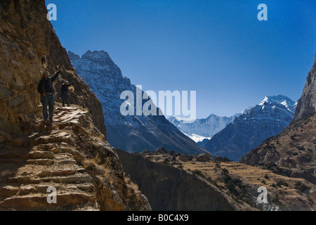 Trekker Wandern auf einem Pfad aus einer Klippe in der Nähe der tibetischen Dorf von PHU ANNAPURNA CONSERVATION AREA NEPAL Herr geschnitzt Stockfoto