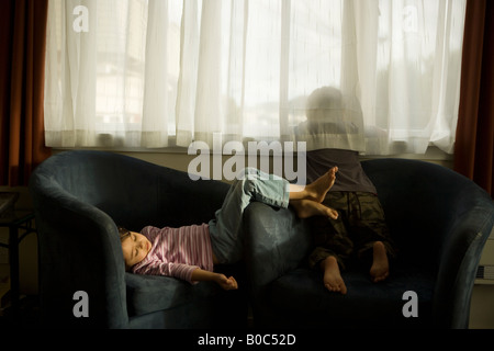 Junge im Alter von sechs blickt Fenster Mädchen im Alter von vier Jahren sitzt im Sessel Motelzimmer Wellington New Zealand Stockfoto