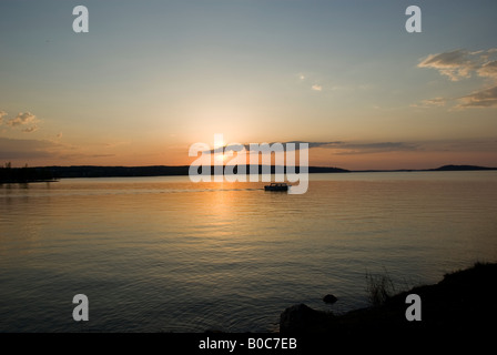 Ein Boot aufbrechen, um den See gegen die untergehende Sonne Stockfoto