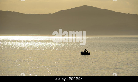 EIN FISCHER GENIEßT EINEN ANGELAUSFLUG AM SPÄTEN ABEND VOR DER KÜSTE DER ISLE OF JURA, NORD-WEST-SCHOTTLAND, VEREINIGTES KÖNIGREICH Stockfoto