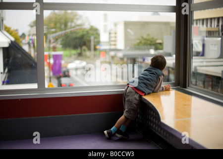 Jungen im Alter von sechs sieht aus dem Fenster einer Bibliothek Stockfoto