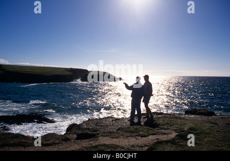An einem klaren Sommertag auf der Cornish stehen Küste zwei Urlauber auf den Felsen an der Treyarnon Bucht in der Nähe von Newquay Strand Stockfoto