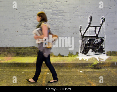 Weibliche Verbraucher unter Einkaufswagen gefangen - ein Bild von The Cans Festival, London Straße Ausstellung Banksy geholfen offen Stockfoto