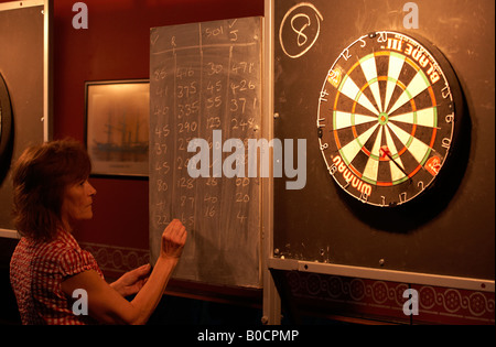 Eine Dame Dartspieler subtrahiert Noten während eines Spiels von 501 Nummern mit Kreide an die Tafel schreiben Stockfoto