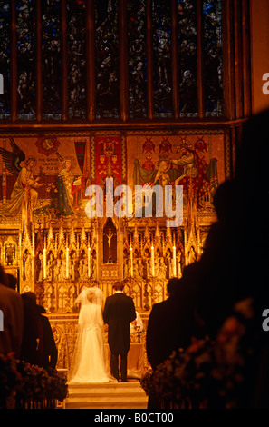 Durch den kirchlichen Gang einer Gesellschaft Hochzeit in Chelsea ein junges Paar auf der Suche sind am Altar vor einer Gemeinde heiraten Stockfoto