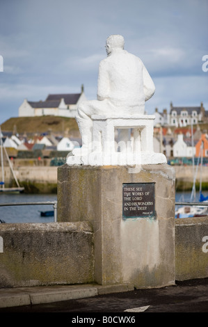 Statur des Sitzens Fischer Blick auf das Meer im historischen Fischerdorf und den Hafen von Findochty, Banffshire, Schottland Stockfoto