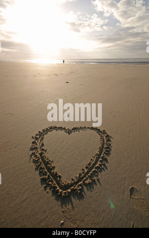 Ein Herz in den Sand am Strand bei Sonnenuntergang gezeichnet Stockfoto