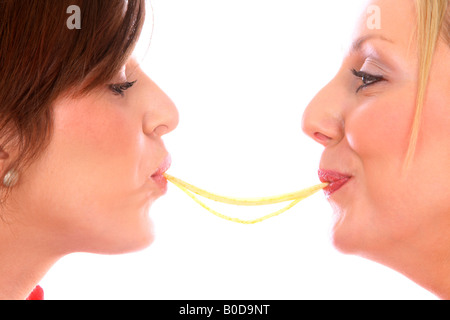 Zwei Freundinnen Teilen und genießen eine große Schüssel mit italienischen Spaghetti Pasta Essen gegen einen weißen Hintergrund isoliert Stockfoto