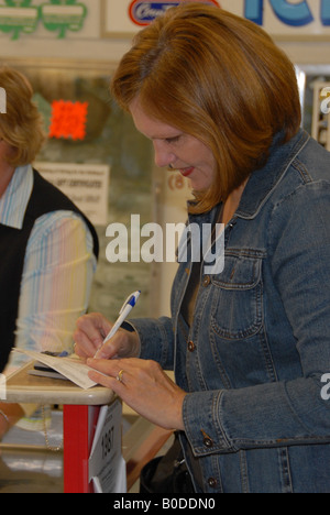 Eine Frau zahlt für ihre Lebensmittel durch Ausstellen eines Schecks. Stockfoto