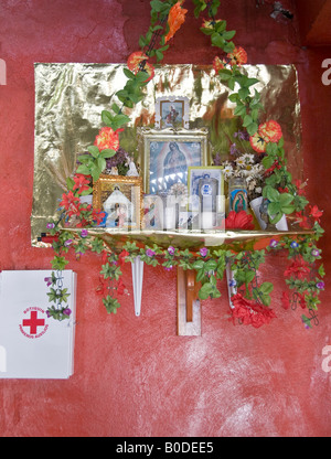 Gerahmte Bilder und Ikonen der Jungfrau von Guadalupe auf Regal Schrein gelegt. Mit Kerzen, Lichterketten und Plastikblumen. Stockfoto