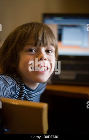 fünf Jahre alter Junge lächelnd vor Computer-Monitor-Arbeitsplatz Stockfoto