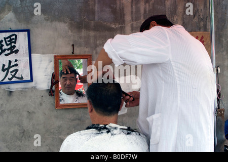 Ein Mann bekommt einen neuen Haarschnitt von Straße Barbier Peking China Stockfoto