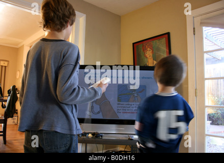 zwei Kinder spielen Wii Videospiel auf großen Bildschirm TV-zu Hause Stockfoto