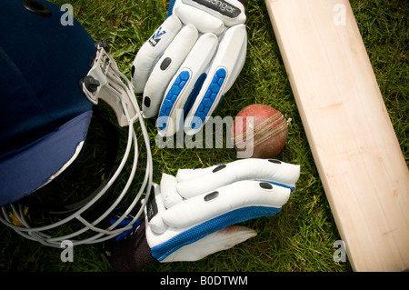 Cricket-Schläger-Ball-Handschuhe und Helm auf Rasen Stockfoto