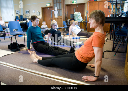 Frau Lehrer unterrichten eines Erwachsenen Yoga-Kurs in einem lokalen Gemeindezentrum Penparcau Sozialsiedlung Aberystwyth Wales UK Stockfoto
