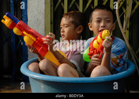 zwei kleine Junge sitzen im Kunststoff-Eimer mit Wasser genießen Songkran Festival, Bangkok, thailand Stockfoto