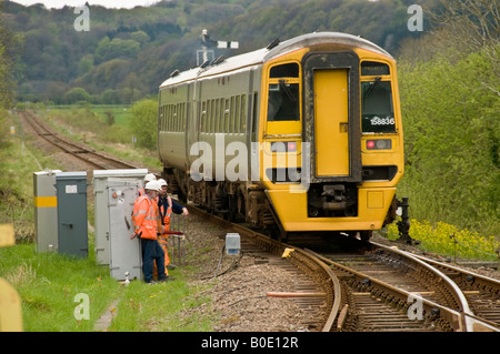 Arriva Wales DMU trainieren auf der eingleisigen Cambrian Küste vorbei an einer Gruppe von Ingenieuren, die in den Punkten arbeiten Stockfoto