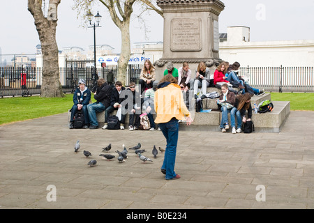 Studenten sitzen auf einem Denkmal und Essen zu Mittag in Greenwich eine Mädchen die Tauben schaut Stockfoto